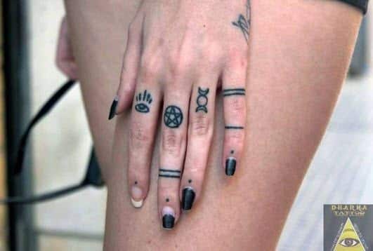 Tatuajes símbolos en los dedos de una mujer
